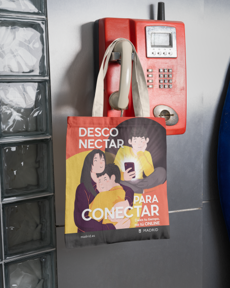 Bolsa de tela con ilustración de personas abrazadas y un chico usando un teléfono y texto sobre conectar con los otros. Campaña publicidad